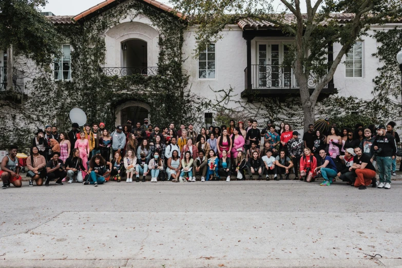 a large group of people standing in front of a large white building