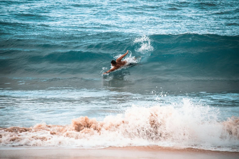 man swimming off the ocean with waves breaking up