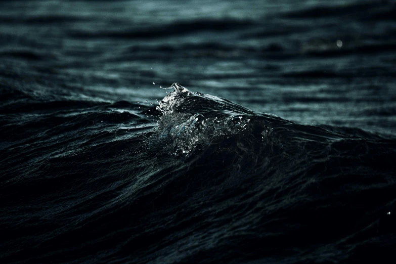 an ocean wave hitting on the beach during twilight