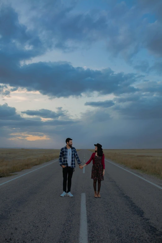 two people standing on the edge of an empty road