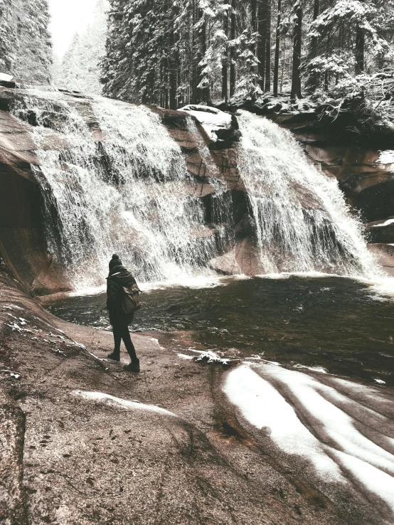 a man is standing in front of a waterfall