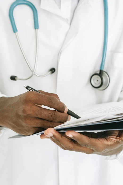 doctor writing on book with pen while holding clip board