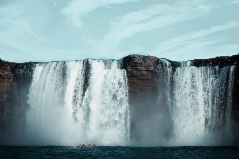 a boat in the water near a tall waterfall