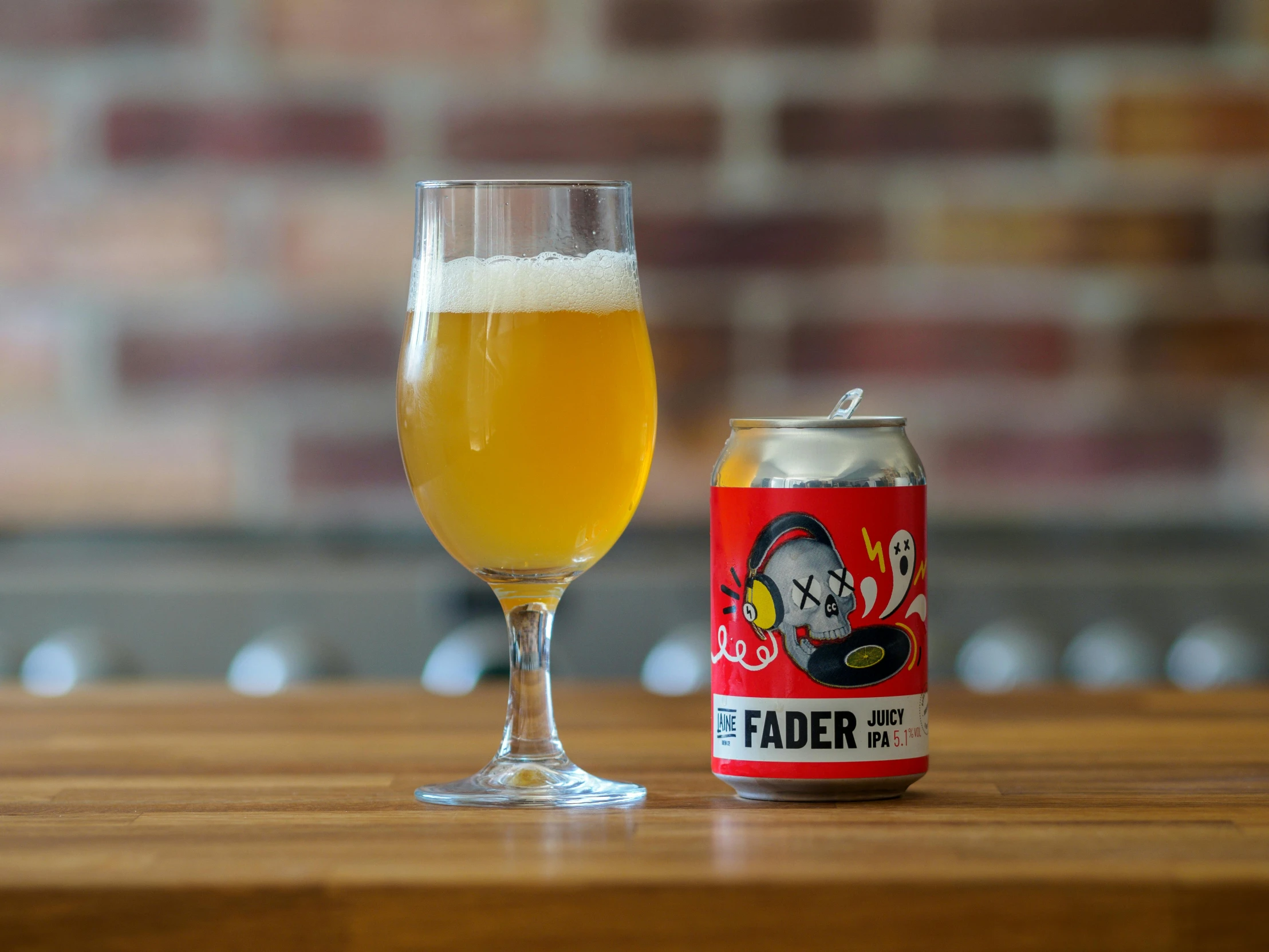 a glass next to a beer can filled with beer