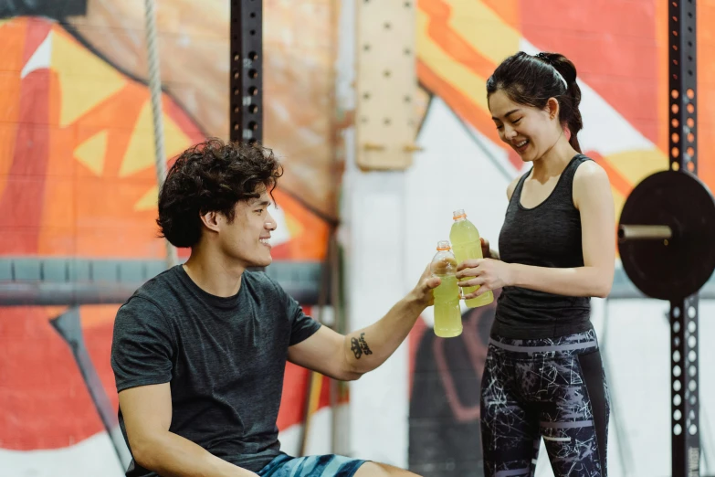 a man is holding a water bottle and a woman sits on the bench