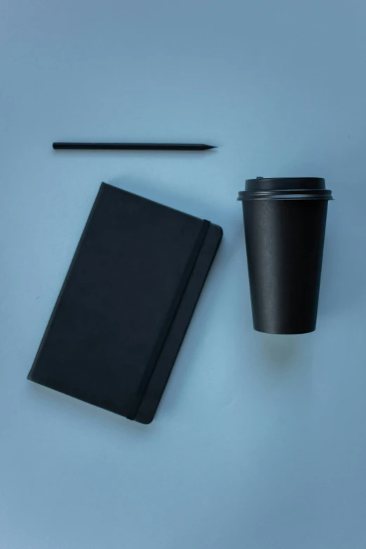 a black notebook, pen and a cup of coffee