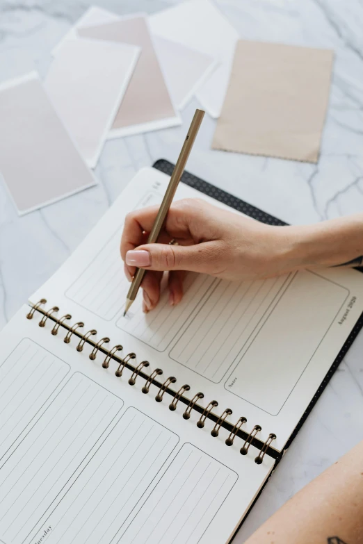 a person writing on a white paper with pencil