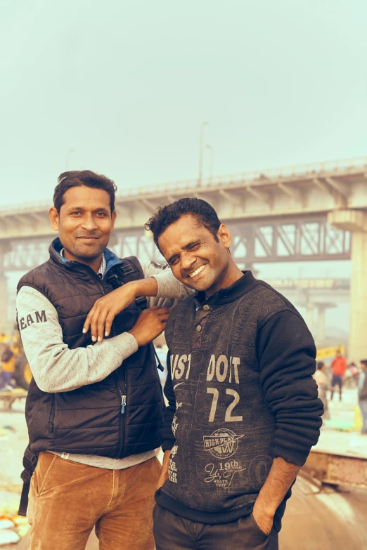 two men are standing in front of the bridge