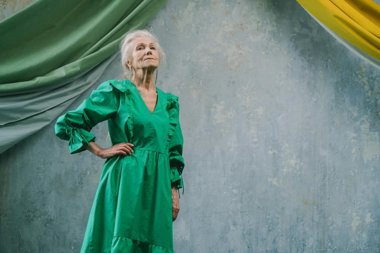 a woman wearing green leaning against a wall