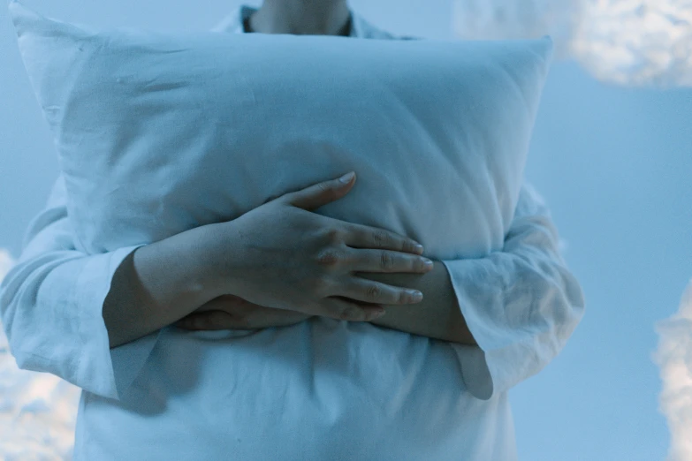 a woman wrapped in a pillow with one hand on top