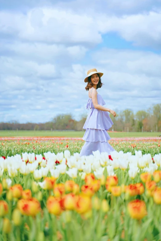 a woman is in the middle of a field full of flowers