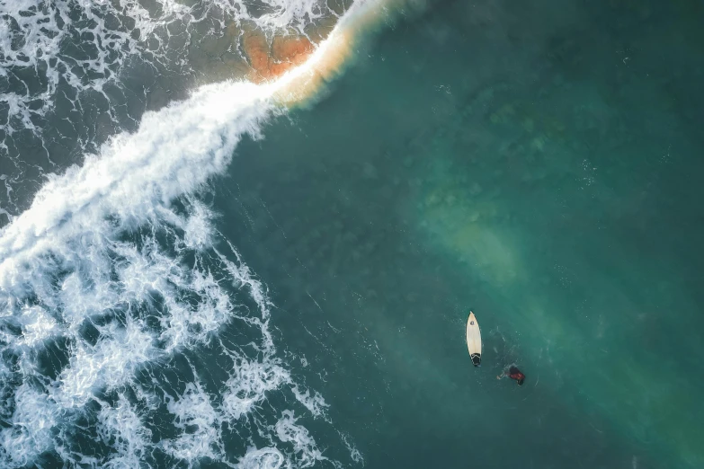 an aerial view of a surfer riding an orange surfboard