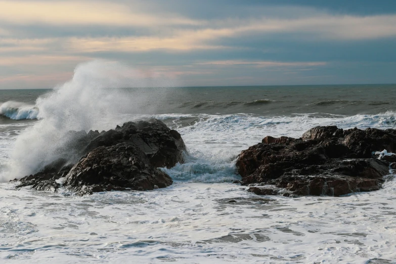 a couple of rocks with some water crashing on it