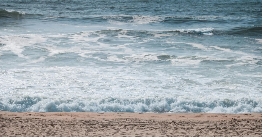 a person is walking alone on the beach next to the ocean