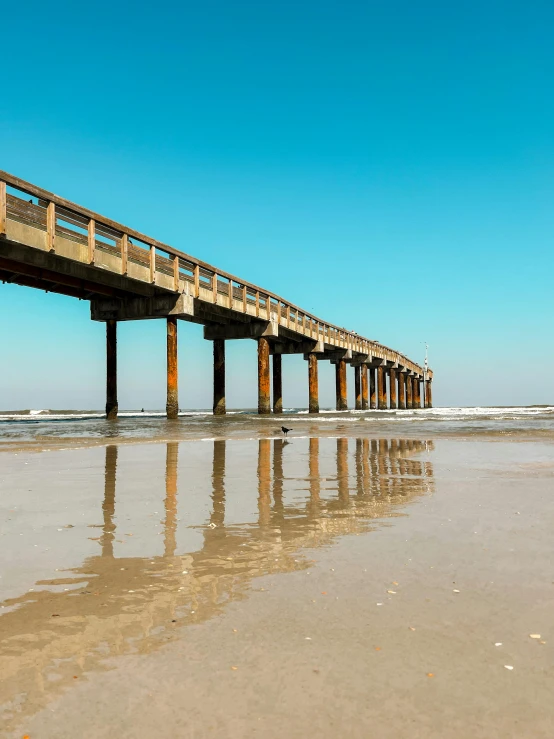 a wooden pier sitting over the top of a sandy beach