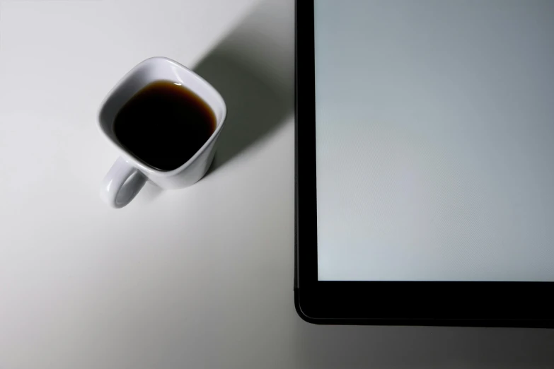 a cup of coffee sits in front of a tablet