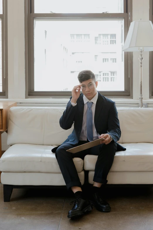 a man sitting on a white couch talking on a phone