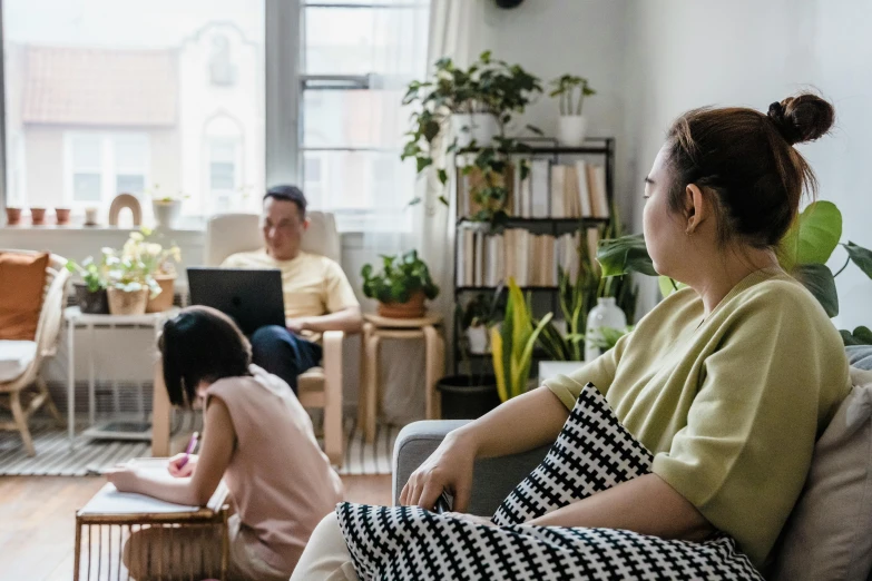 three people sitting on the couch in a living room