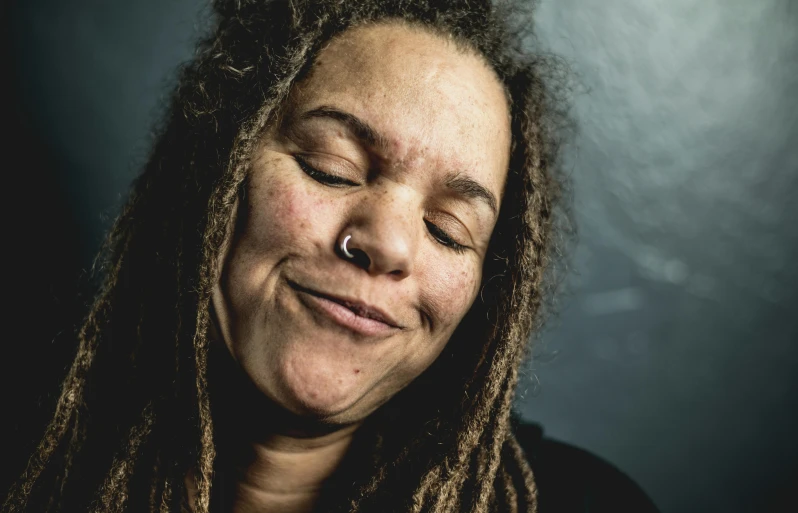 a woman with dreadlocks is smiling and posing for the camera