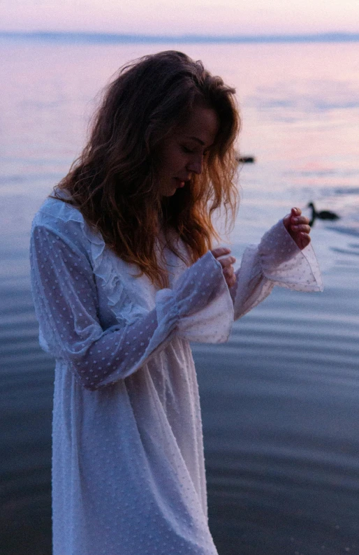 a woman standing near a body of water holding a piece of cloth