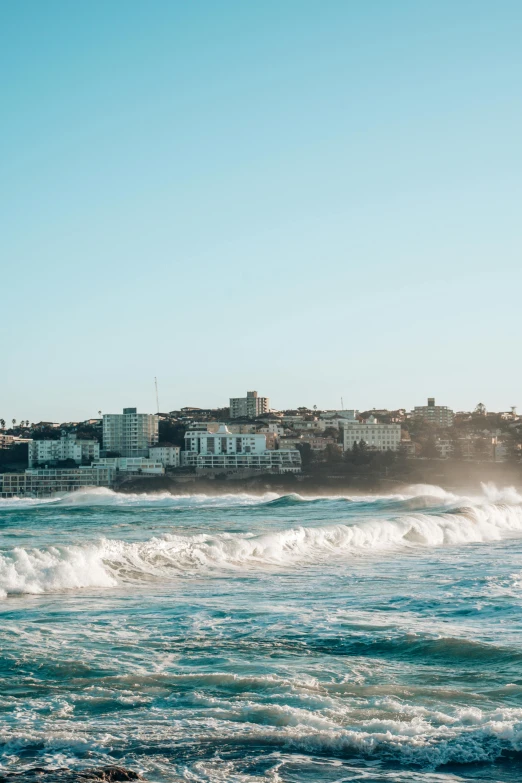 two surfers are in the water and a city is seen in the distance