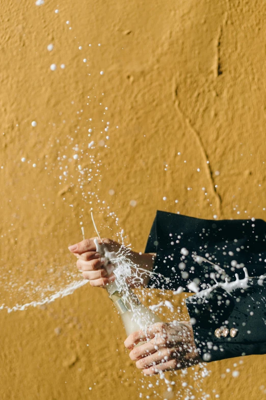 person holding water in their hands near sand