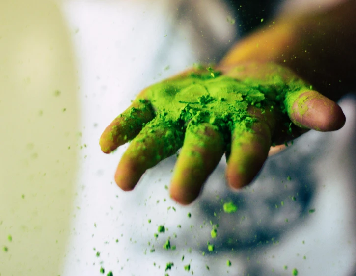 an image of a hand holding a handful of green powder