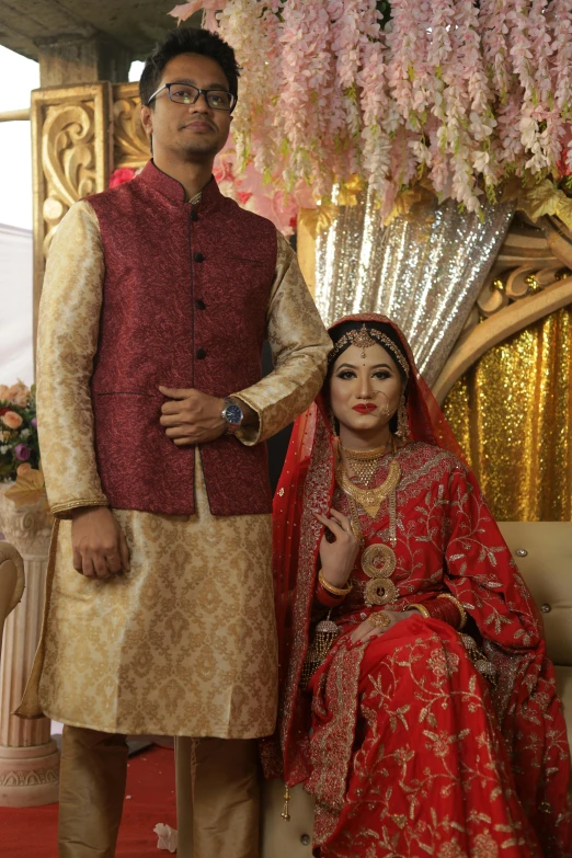 a man standing next to a woman in a red and gold dress