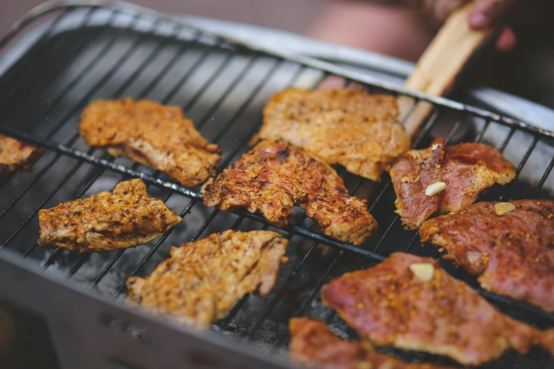 meats being cooked on a small grill being used to cook