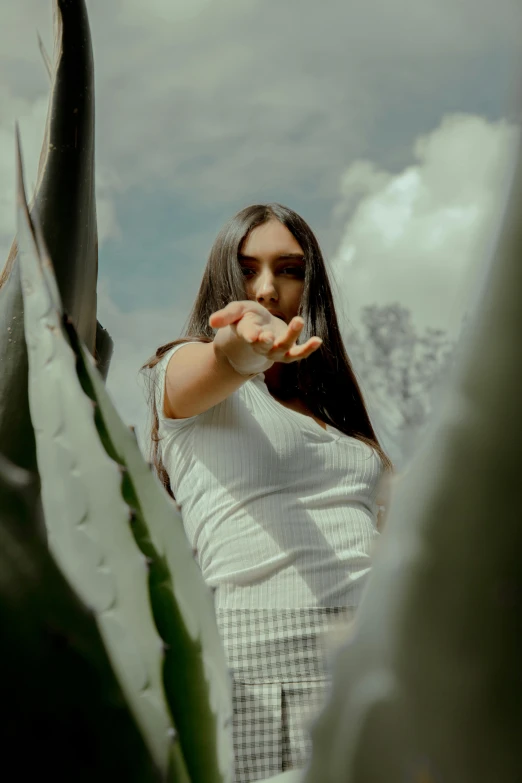 a woman posing by a cactus, she has a point at the camera