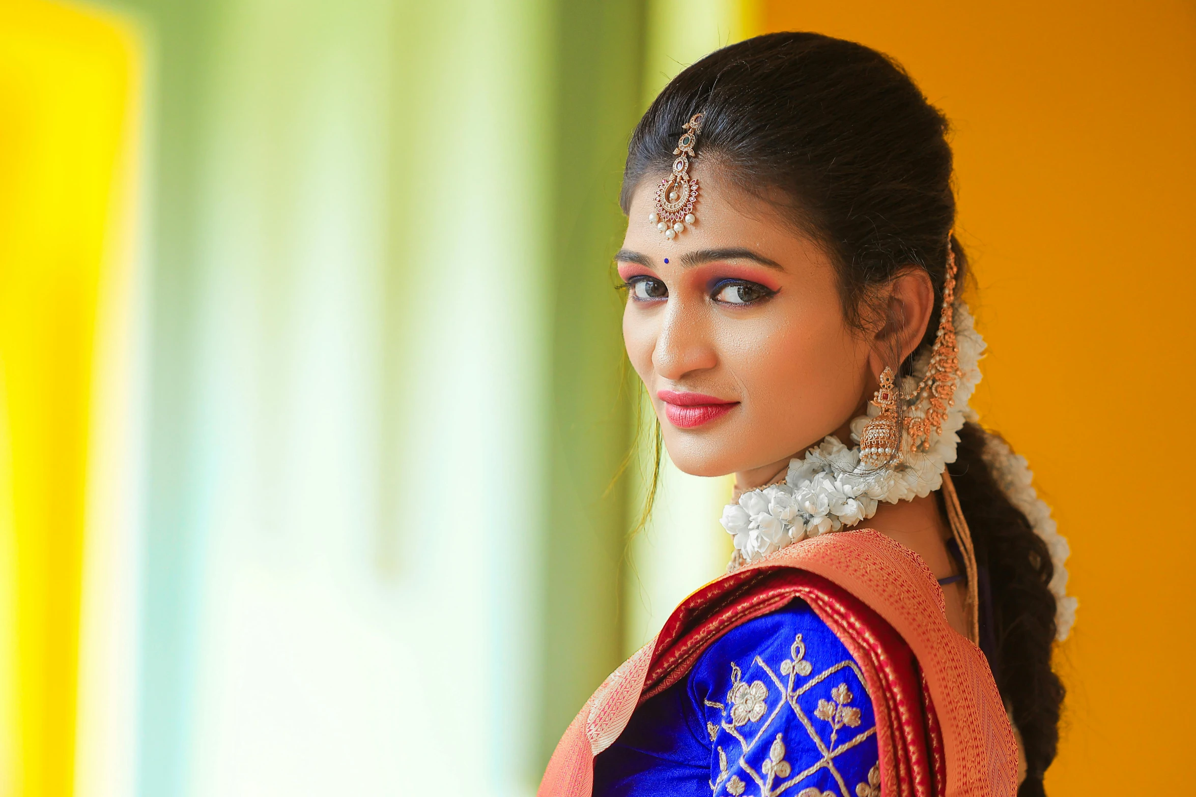 a woman wearing an indian blouse and earrings, looking to her left