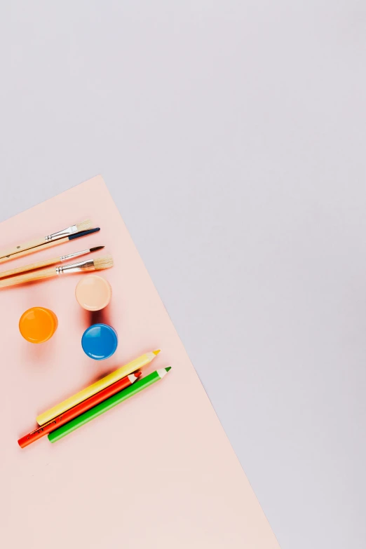 an assortment of pens and pencils next to paint