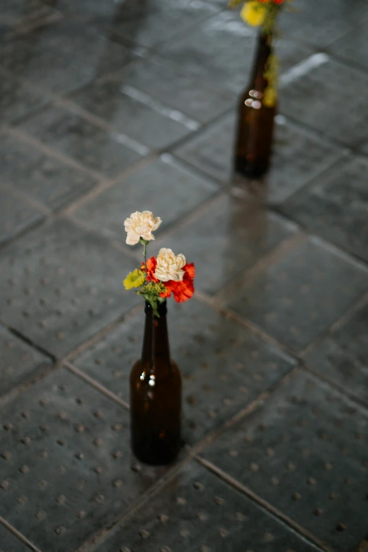 two brown bottles with flowers are sitting on the ground