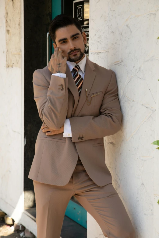 a man in suit leaning against a wall