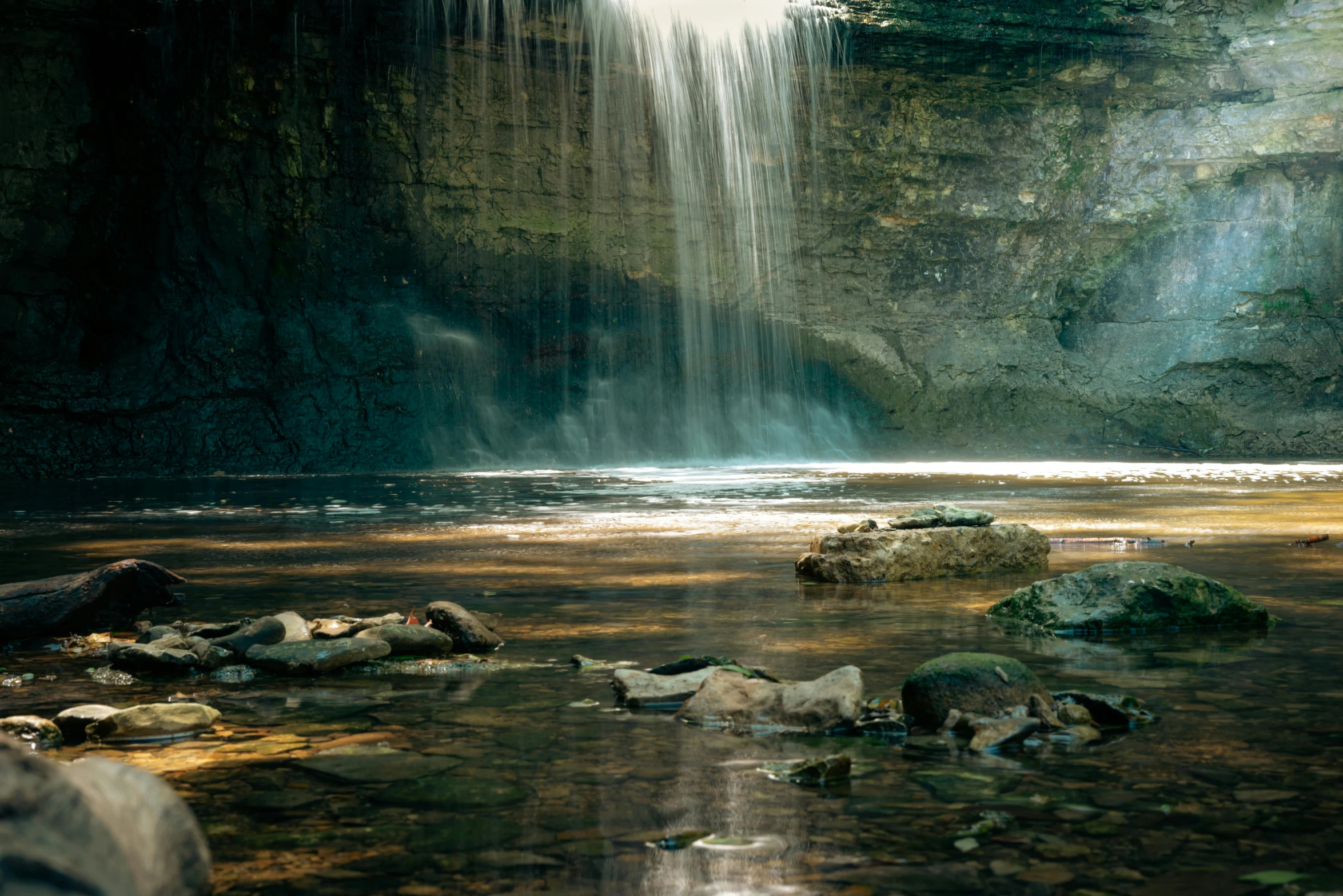 a waterfall in a lush green jungle with sunlight