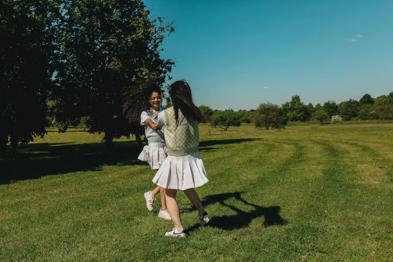 two girls walking in a field with trees