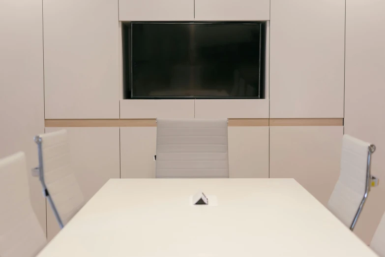 an empty conference room with white chairs and a large projection screen