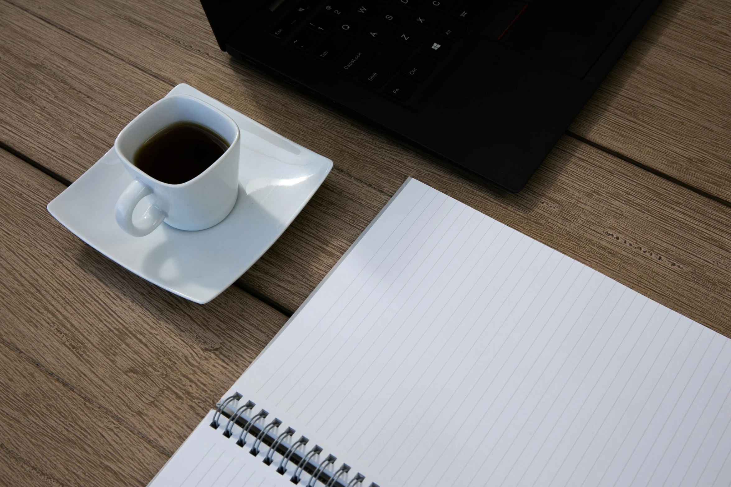 coffee and notebook sitting on a wooden desk