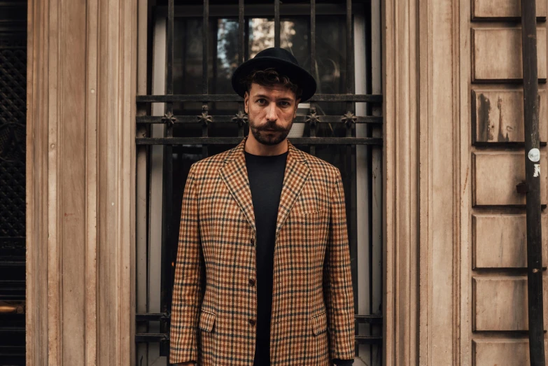 man wearing checkered coat standing in front of a window