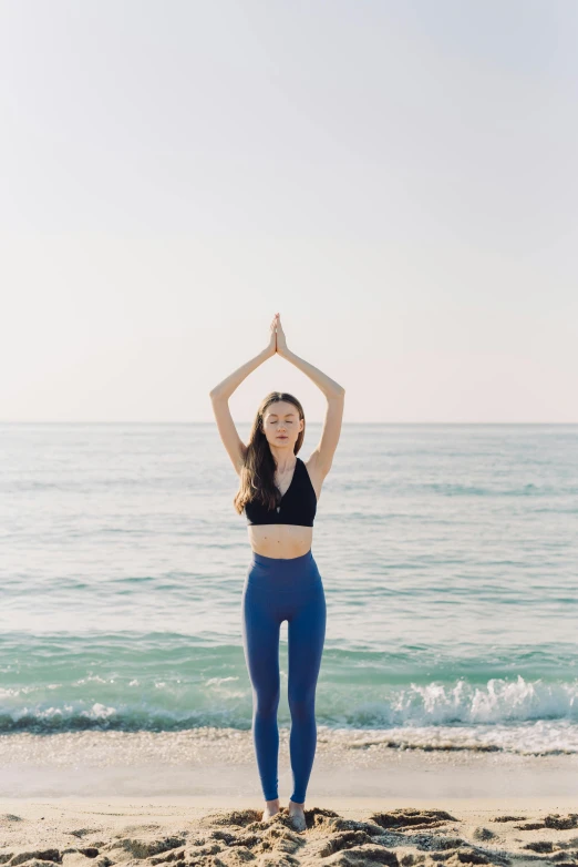 a woman wearing blue pants stands in front of the ocean