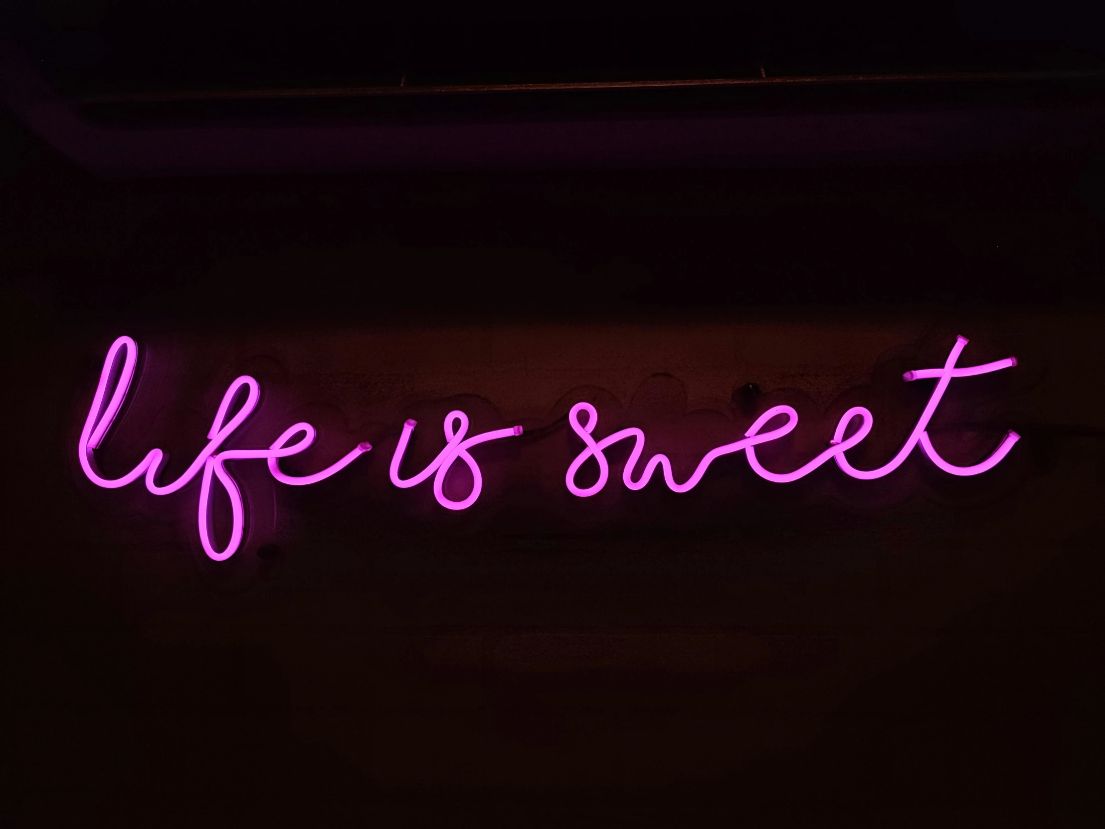 a purple neon sign is glowing in the dark