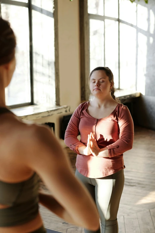 woman with her eyes closed in yoga pose, looking out window