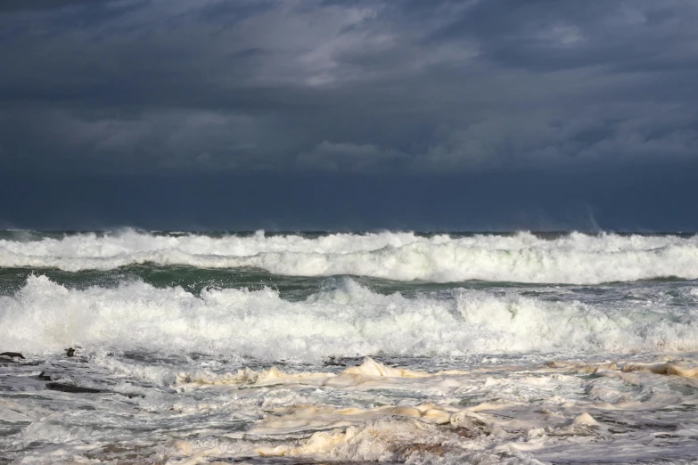 a large ocean wave with white spray coming over the top