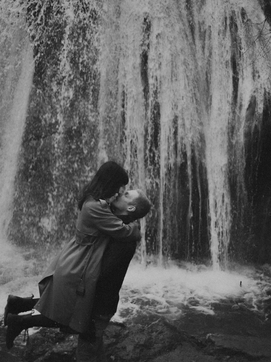 a woman sitting on a rock near a waterfall