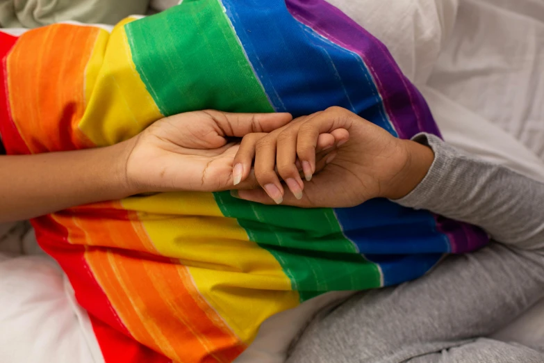 a child is snuggled in a blanket with their hand on a rainbow colored pillow