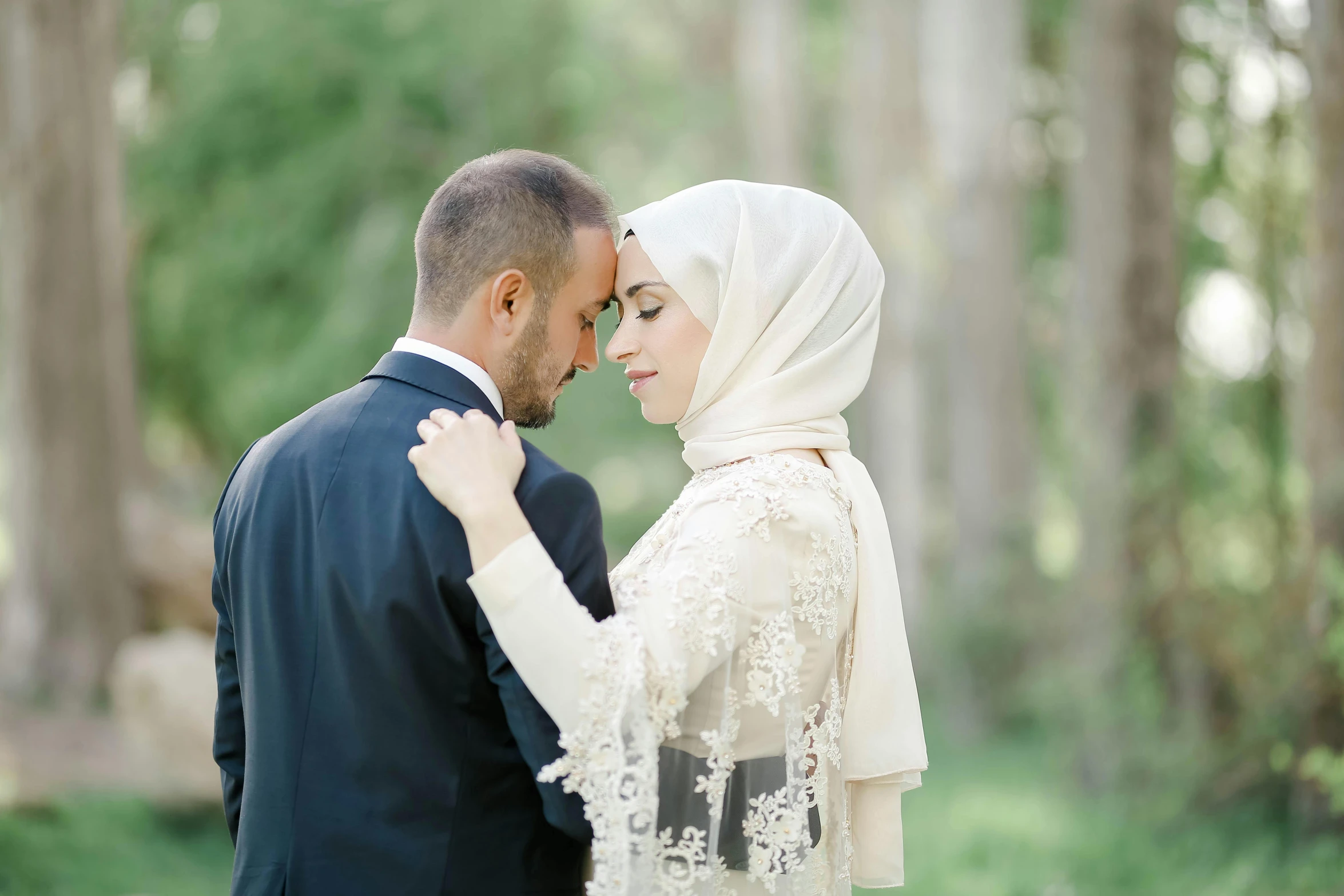 an omani bride holds her groom's arm in the forest
