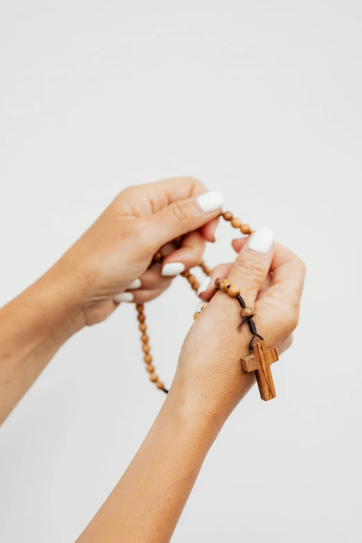 a woman holding up a wooden rosary with beads