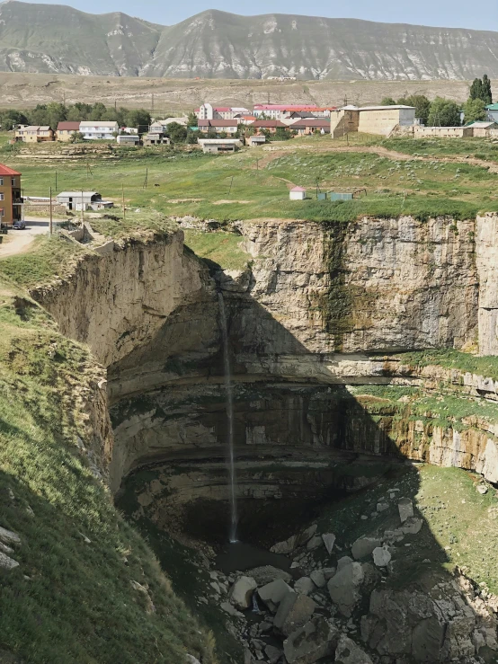 this image shows a cut out of the ground where an open pipe was placed and in the ground, there are several buildings with lots of them near mountains, on the far