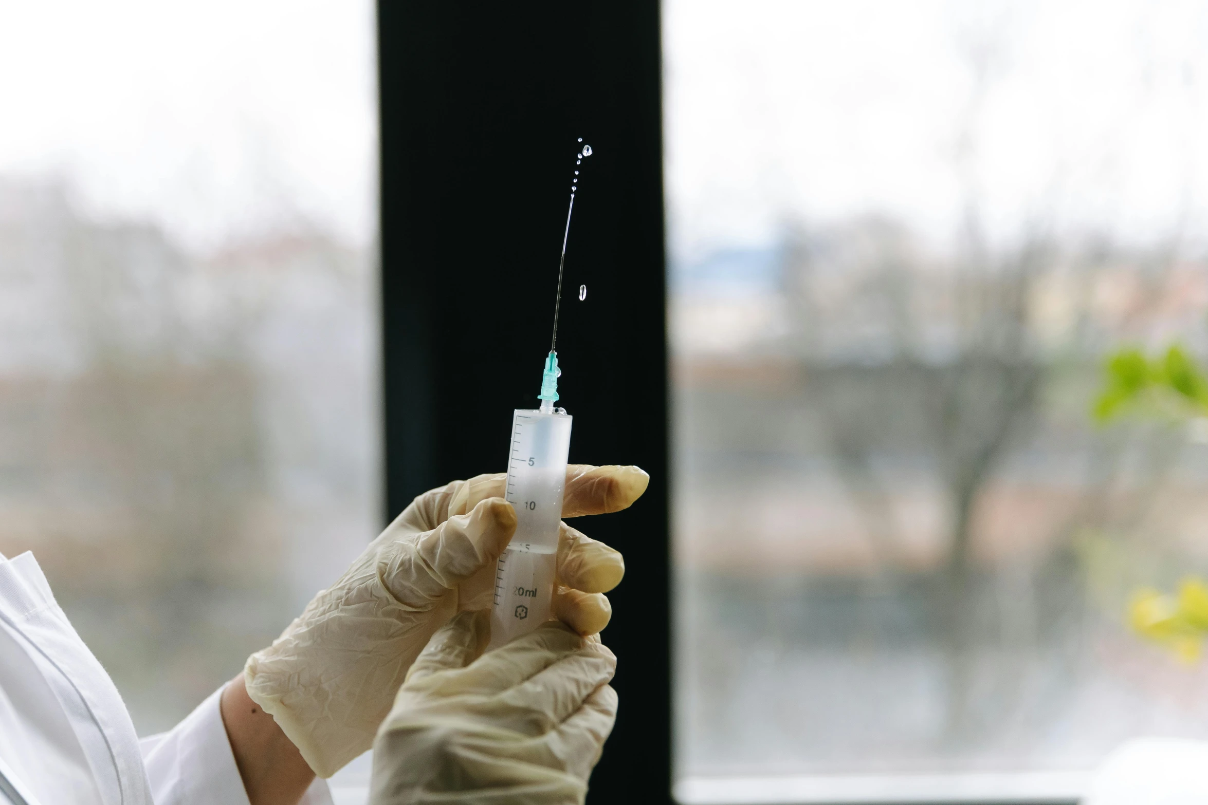 someone in white gloves holding up an iv for medical purposes