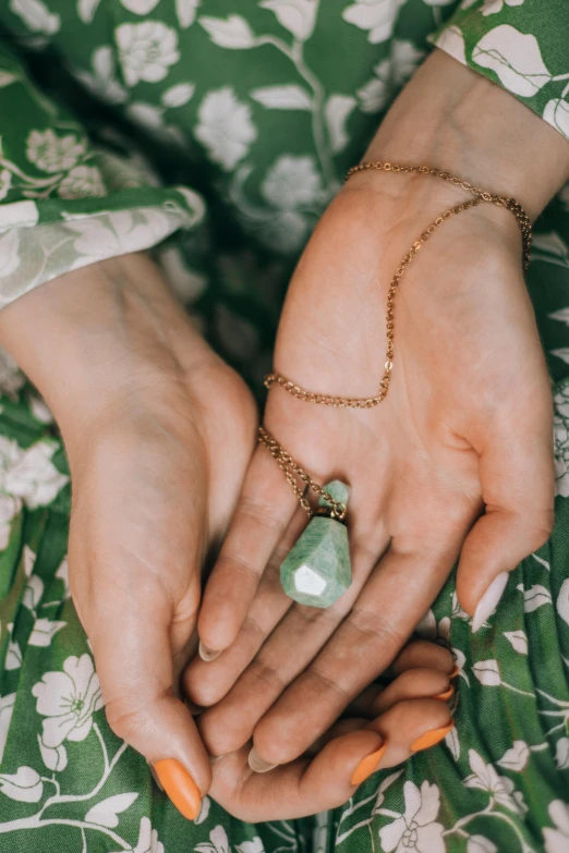 a woman's hands hold a small crystal necklace